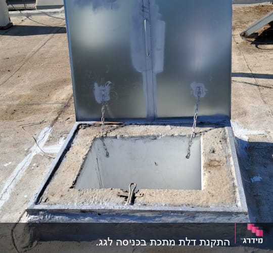 פתח גג עם מכסה מתכת וכלים על הגג